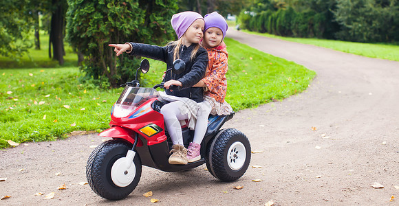 快乐可爱的小女孩 骑摩托车出去外面裙子游戏速度活动晴天运输夹克婴儿玩具童年背景图片