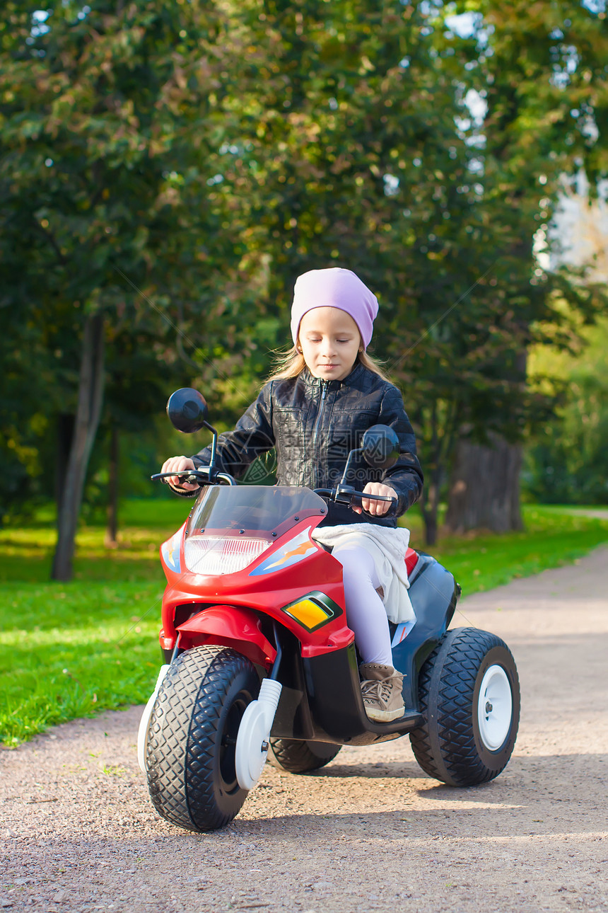 可爱的小女孩在玩具摩托车上玩得开心速度阳光娱乐喜悦童年微笑运动运输姐姐幼儿园图片