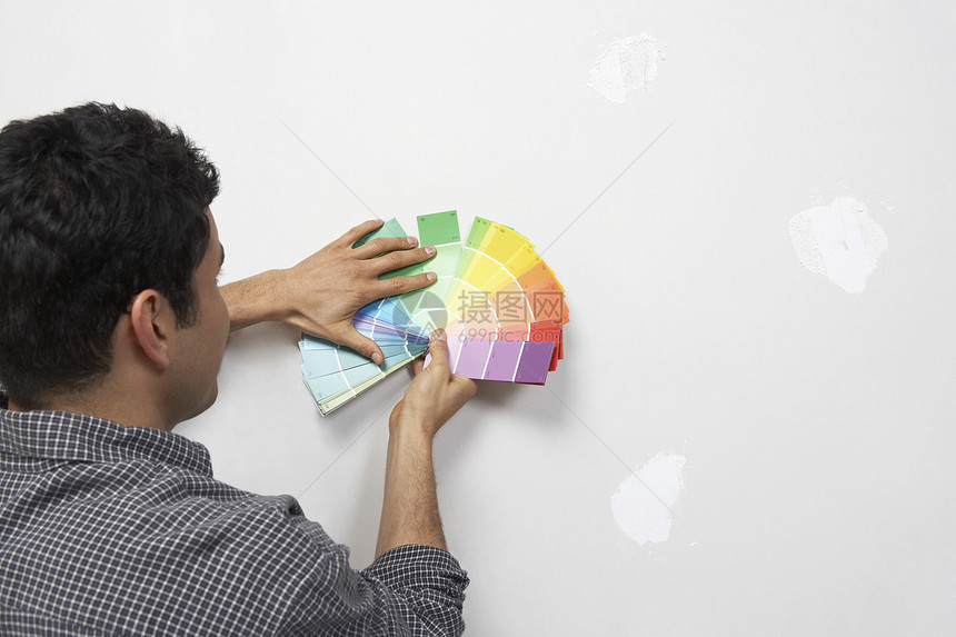 男子在内部墙壁反视图下持有油漆颜色样本图片