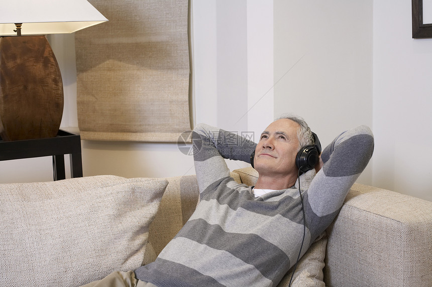 中年男子在客厅用耳机收听音乐图片