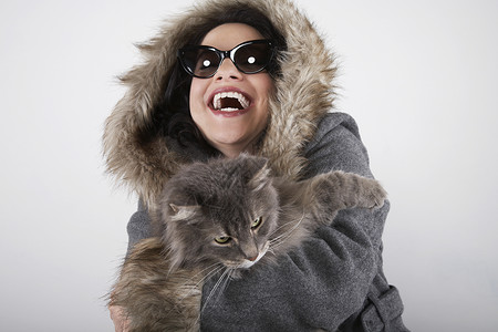 笑着的猫戴蒙头大衣并笑着猫咪的女人背景