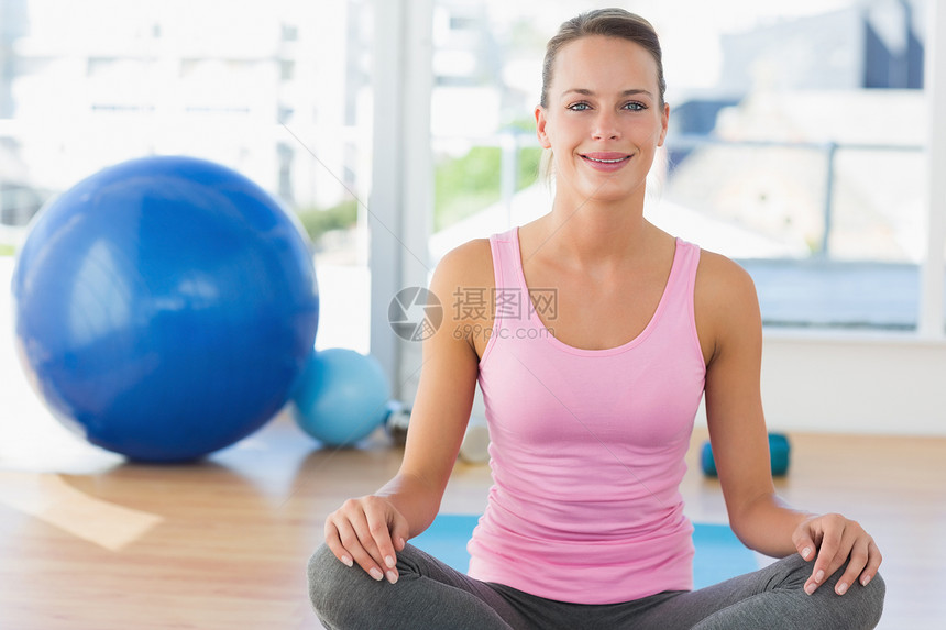 坐在健身工作室的微笑的年轻女子生活方式闲暇女性身体护理健身房运动服女士调子姿势图片