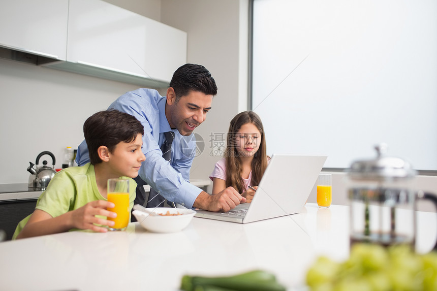父亲使用笔记本电脑 孩子在厨房吃早餐女孩女性技术房子果汁兄弟团结兄弟姐妹餐桌童年图片