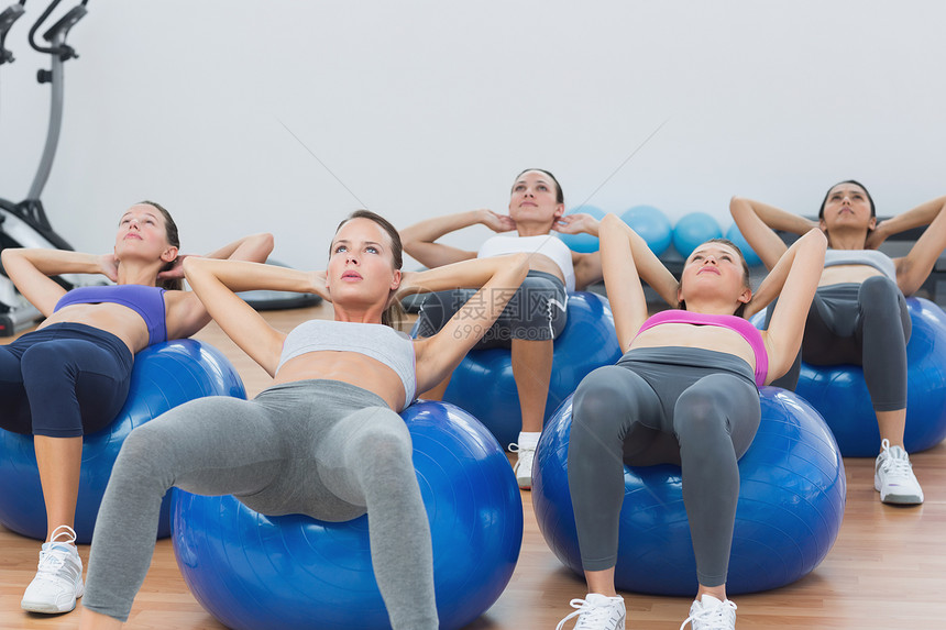 在健身球上做腹部骨折的班级混血女性核心锻炼培训师瘦身身体运动服运动员仰卧起坐图片