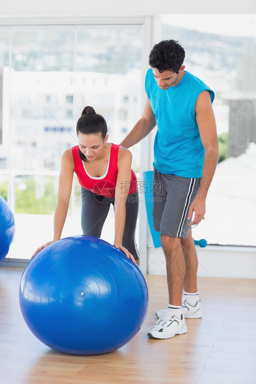 男性教练员帮助妇女在体操中锻炼运动男人拉伸火车训练身体女性平衡健身讲师图片