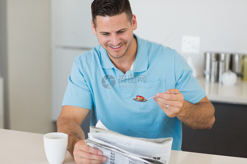 男人在餐桌边吃早餐时看报纸图片