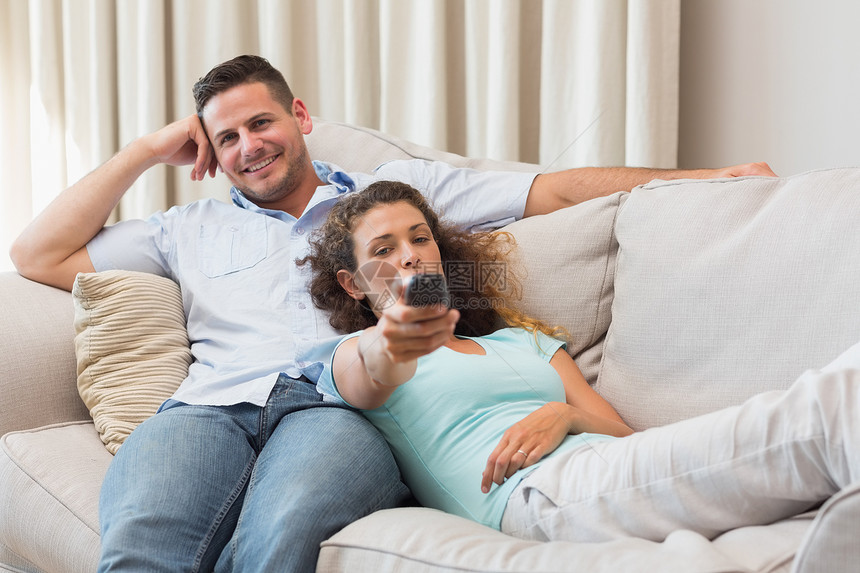 年轻夫妇看电视家居便服夫妻说谎男人沙发娱乐异性恋倾斜遥控图片