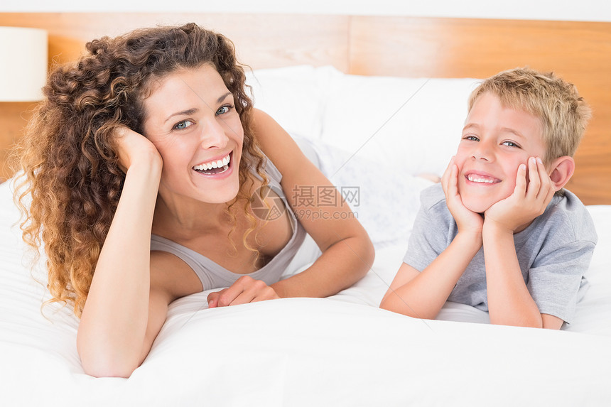 快乐的母亲和儿子躺在床上看着镜头看图片