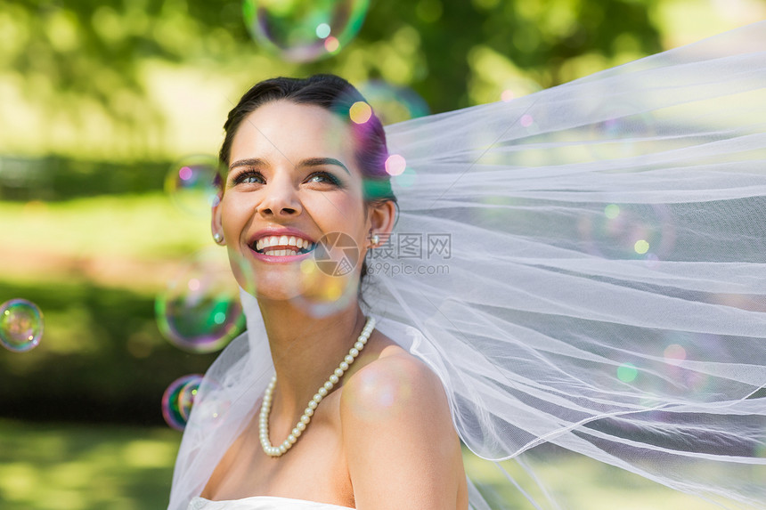 美丽的新娘看着公园的肥皂泡泡图片