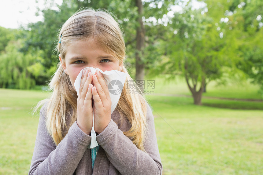 女孩在公园用纸巾打鼻涕组织流感鼻子草地疾病花园女性童年浅色头发图片