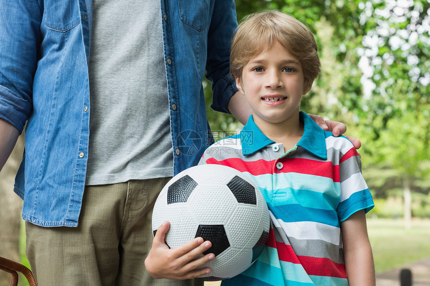 一个男孩除了他父亲外还拿着足球的肖像图片