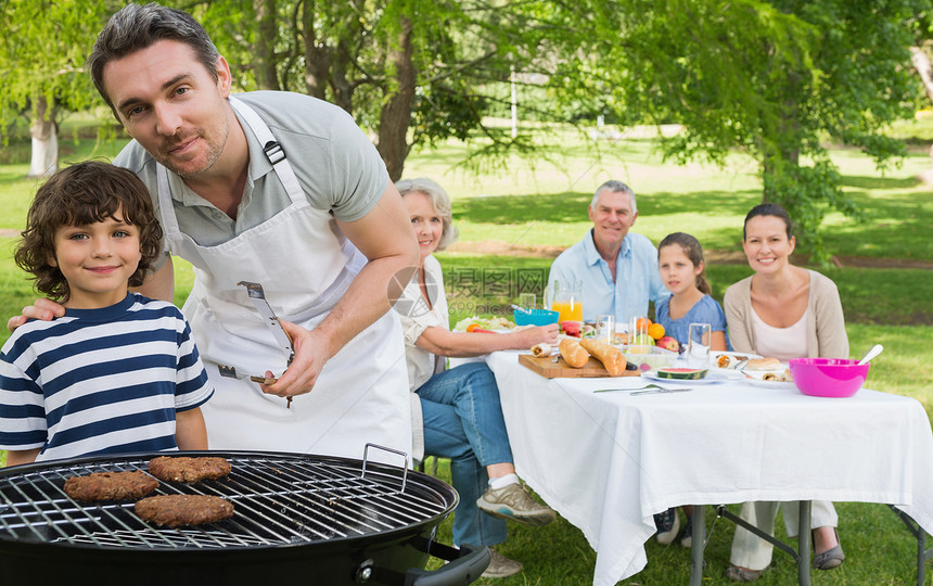 父亲和儿子在烧烤炉上 家人一起在公园吃午饭花园妈妈假期祖母孙子爸爸兄弟男生女性父母图片