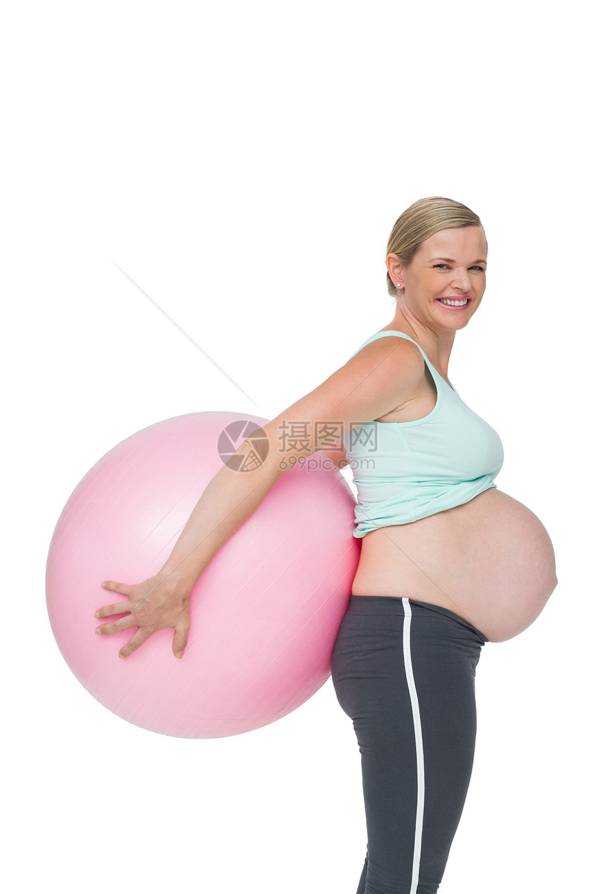 怀着粉红色运动球的快乐孕妇背着她的身后图片
