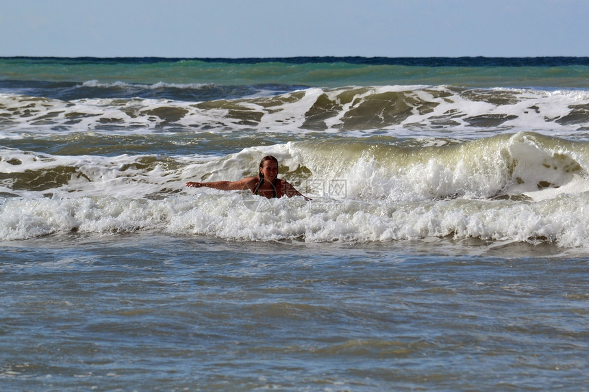 女人在海中对抗大浪波浪飞溅风暴女孩沐浴者图片