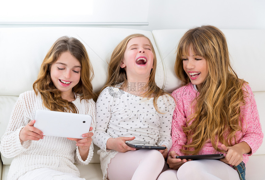 三个小妹妹和三个女孩朋友小组 女孩们一起玩桌边游戏家庭作业药片团体享受孩子孩子们金发沙发朋友们乐趣图片