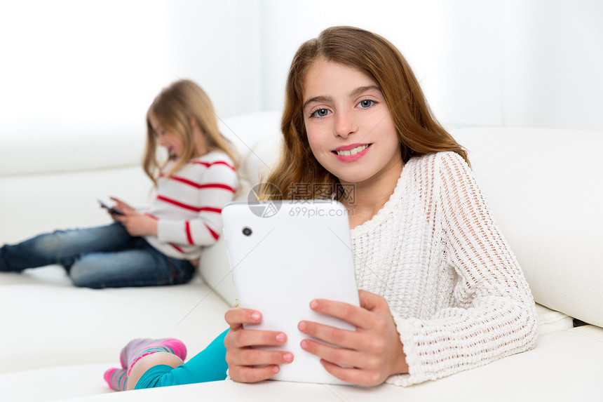 女孩在沙发上玩平板电脑的女孩学生家庭作业药片屏幕乐趣家庭姐妹朋友们孩子们游戏图片