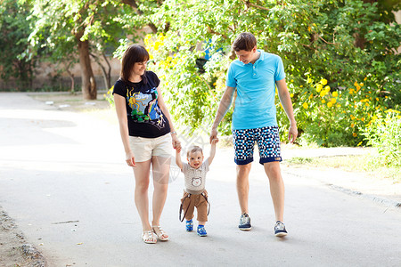 母亲和父亲走路的小孩假期公园父母爸爸婴儿幸福快乐喜悦家庭微笑闲暇高清图片素材