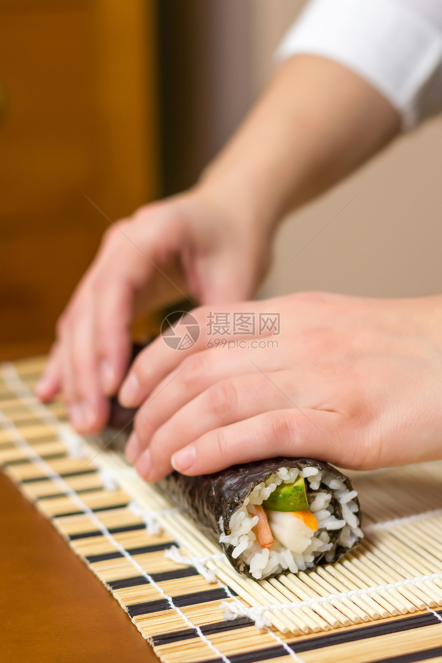 女厨师的手卷起日本寿司黄瓜竹子女性鱼片女士午餐饮食大豆海藻食物图片