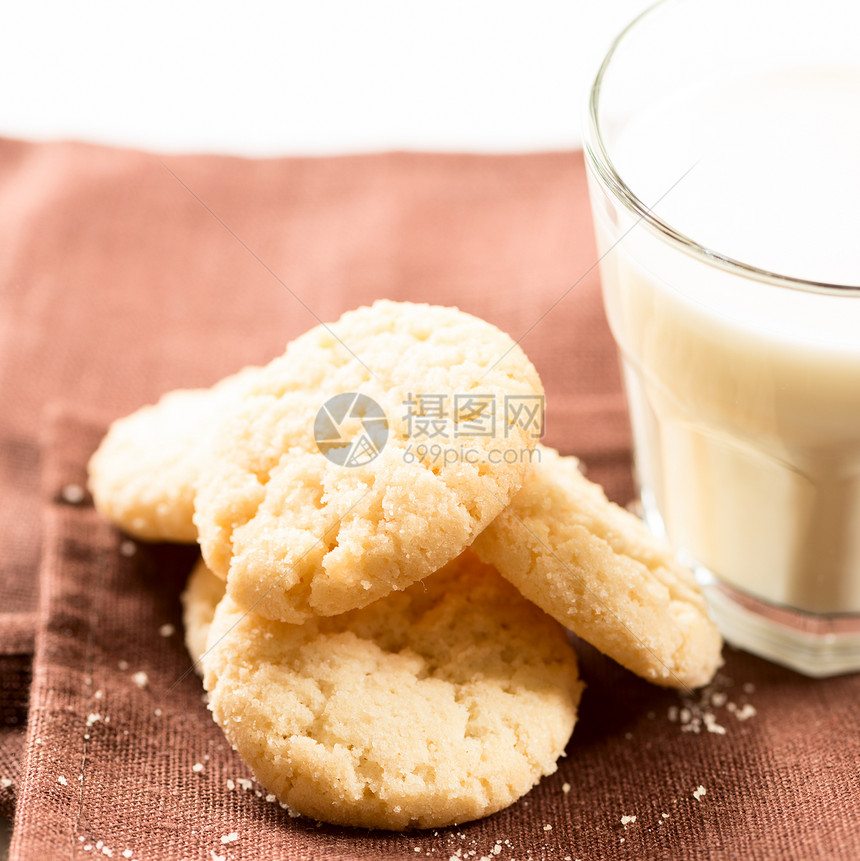 餐巾纸广场上的饼干和杯装牛奶图片