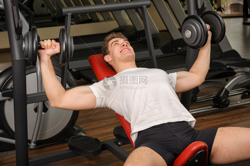青年男子在健身房做邓宾贝尔加连座记者工作肌肉出汗运动训练哑铃倾斜男人运动员权重卧推图片