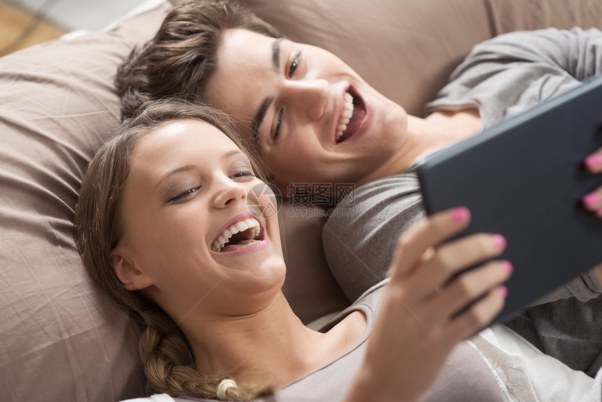 配有数字平板电脑的幸福夫妇女孩卧室男朋友家居友谊两个人数位板女性技术青年图片