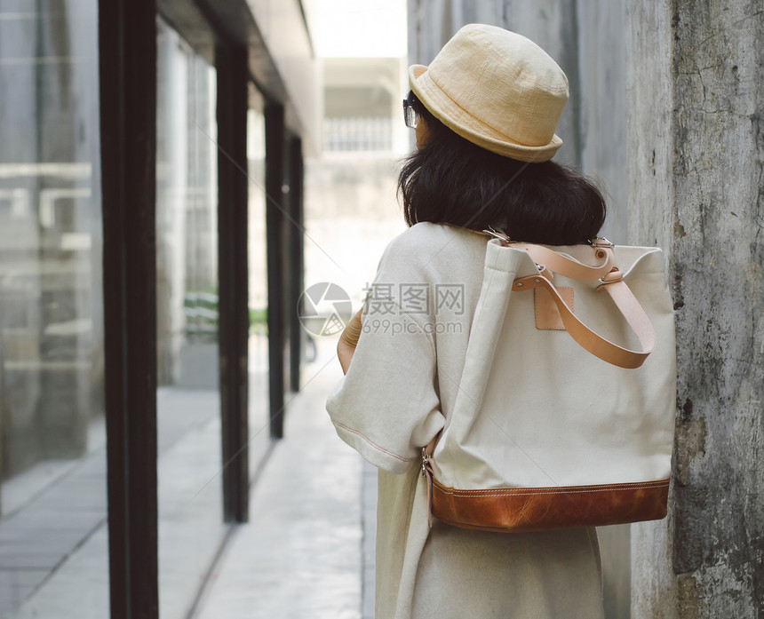 年轻女人拿着帆布袋木头帆布奢华皮革女士旅行女孩棕色手提包街道图片
