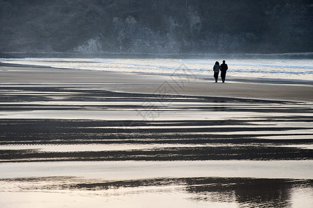 浪漫情侣在海滩上行走夫妻感情拥抱两个人旅游假期太阳目的地背景