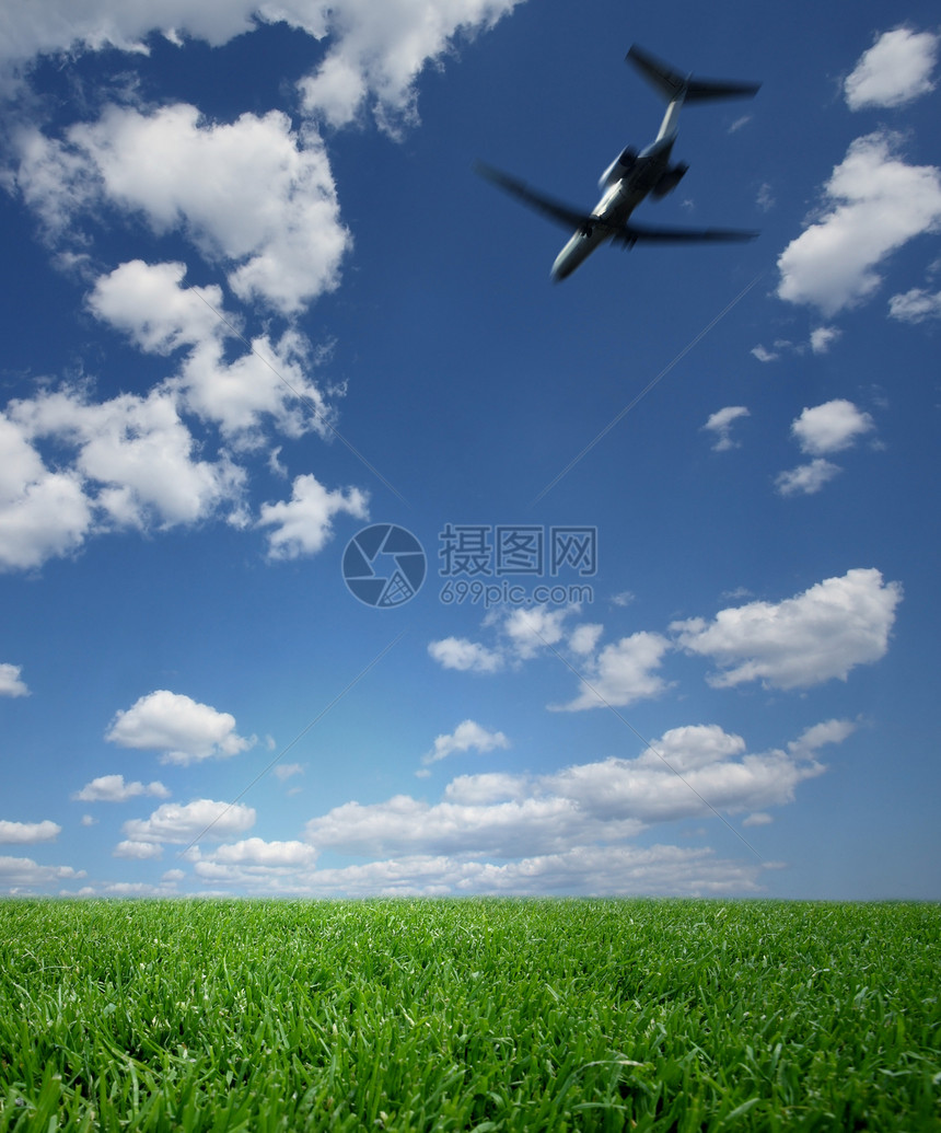 蓝天飞行飞机飞越绿草上空图片