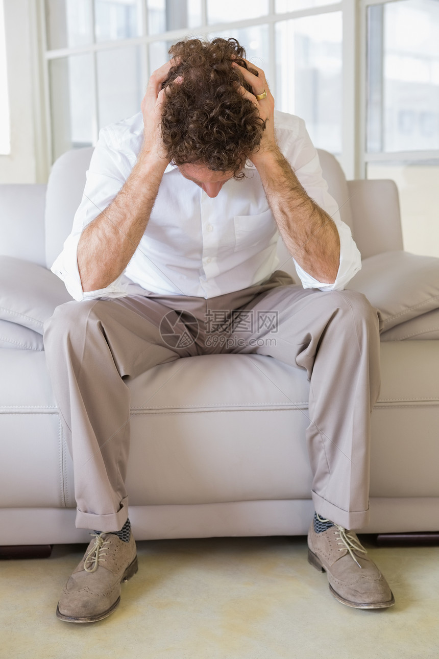 穿着好衣服的男子坐在家里头顶着头坐在家里棕色裤子长椅客厅男性男人闲暇房子褐色衬衫图片