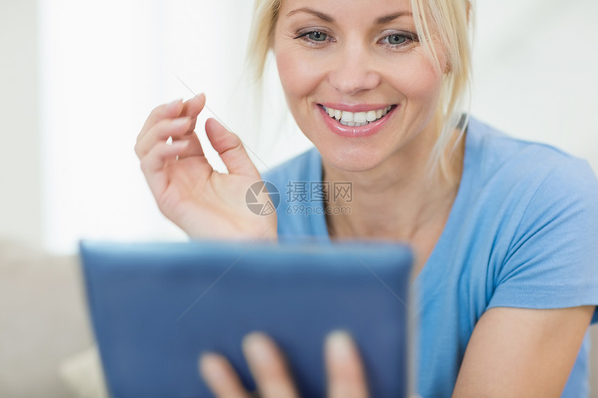 以数码平板电脑特写一个美丽的年轻女子房子微笑头发浅色触摸屏药片闲暇金发金发女郎家庭生活图片