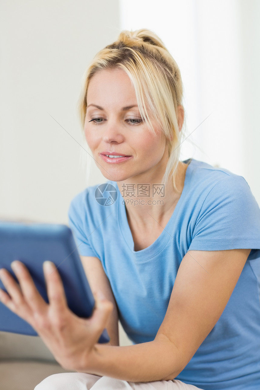 以数码平板电脑特写一个美丽的年轻女子房子金发头发蓝色金发女郎女士触摸屏浅色女性客厅图片