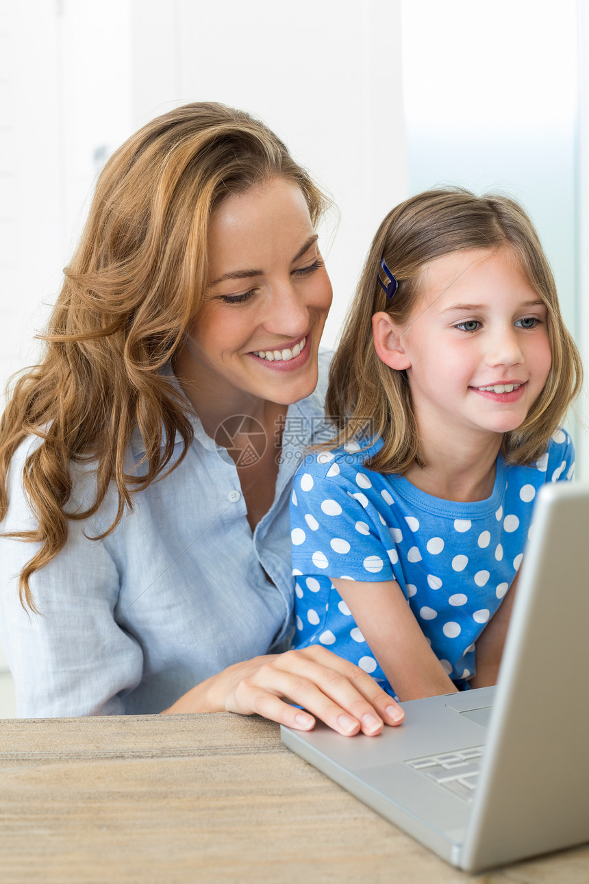 母亲和女儿使用手提笔记本电脑女孩女性学习家居技术教学房子女士便服棕色图片