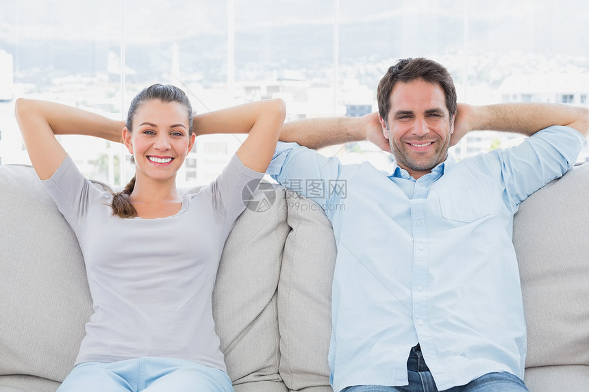 快乐的一对情侣在沙发上放松 在镜头面前微笑着笑双手住所女性夫妻房子长椅家庭男性感情男人图片