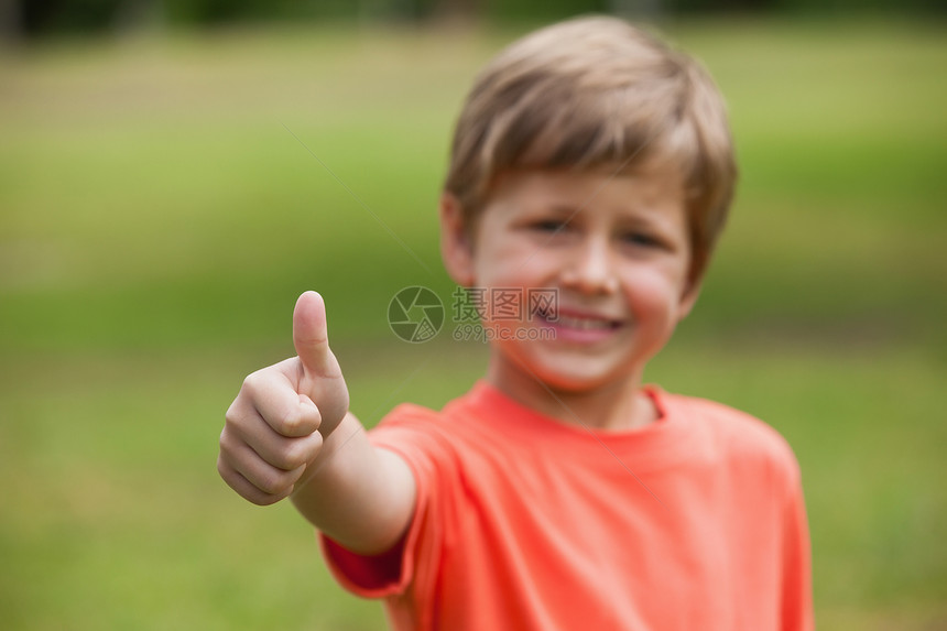 微笑的年轻男孩在公园大拇指图片