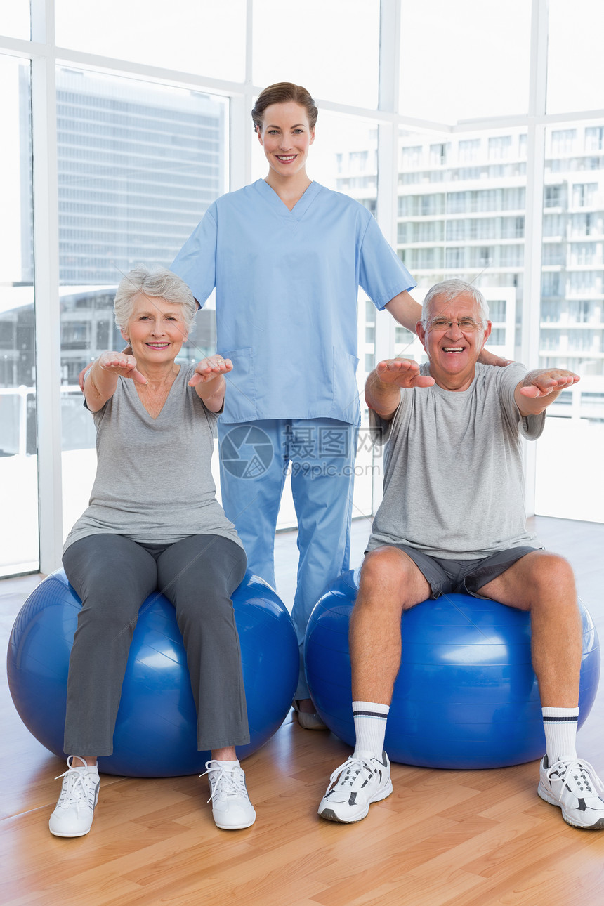 女性治疗师协助老年夫妇锻炼的女性治疗师医院帮助身体成人医务室运动服医生理疗男性健身房图片
