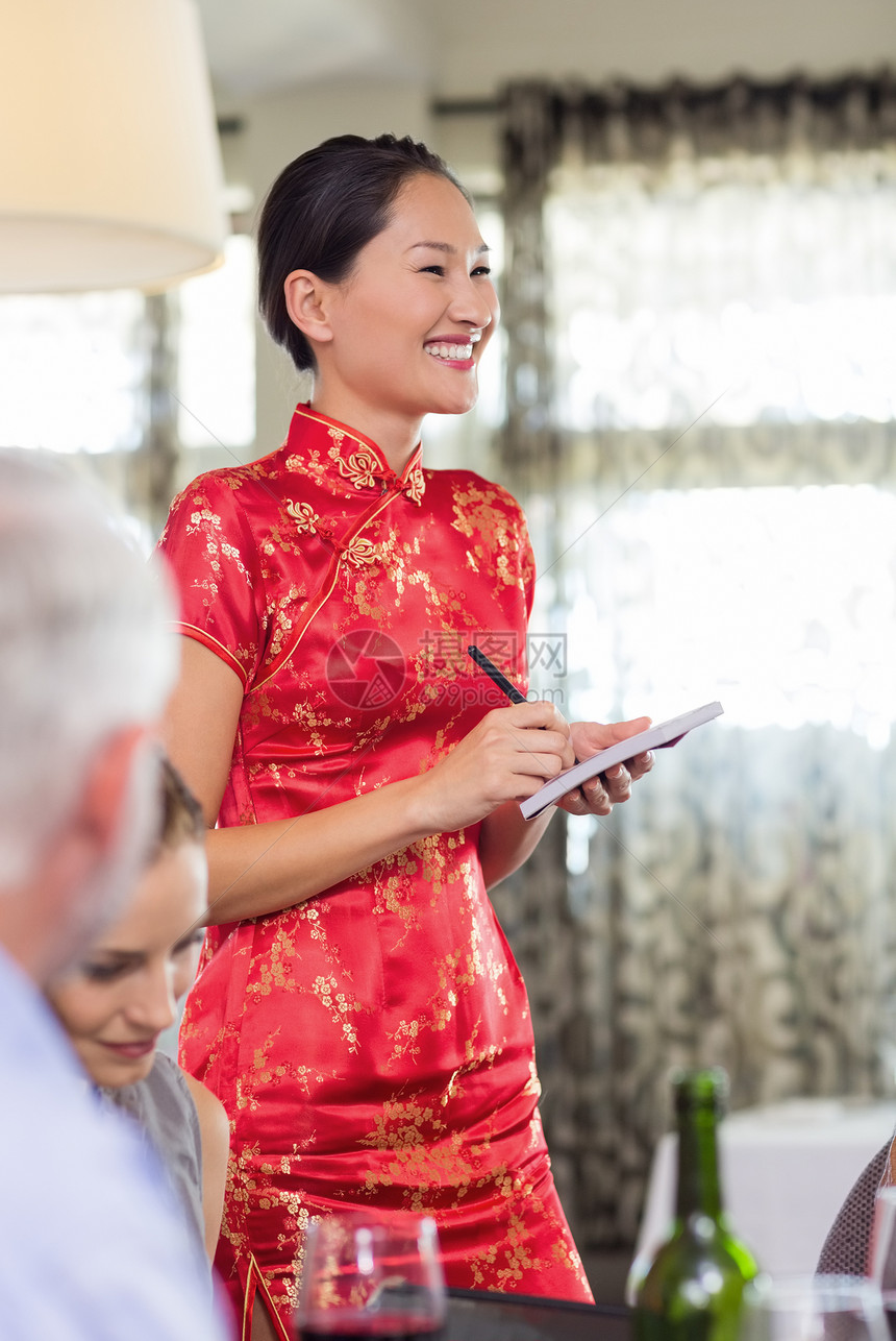 与餐厅餐桌上的人一起微笑的女服务员图片