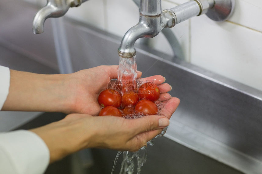 在水龙头下洗樱桃西红柿厨师图片