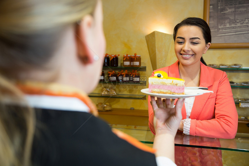 女服务员向咖啡馆的顾客提供蛋糕图片