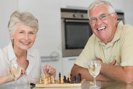 玩象棋和喝白酒的老夫妇微笑夫妻家庭老年成人房子男人退休游戏酒杯桌子背景图片