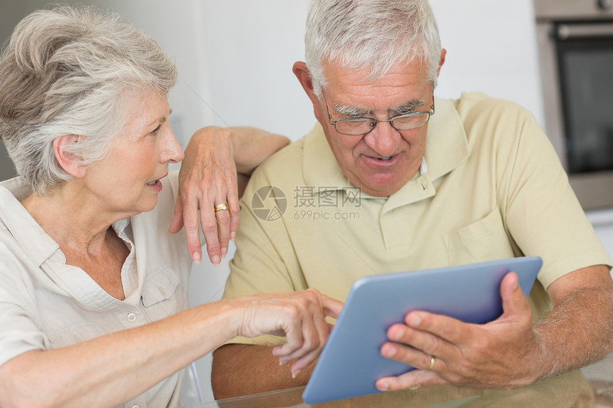在餐桌上使用平板电脑的快乐老年情侣桌子女性男性女士住所房子退休微笑男人困惑图片