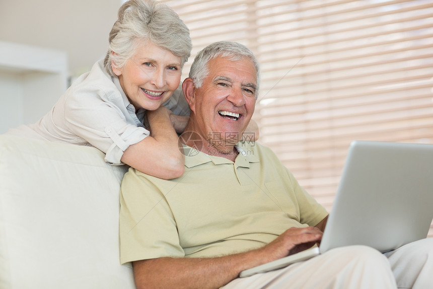 一起用笔记本电脑的老幸福情侣微笑头发女性家庭退休客厅女士长椅闲暇夫妻图片