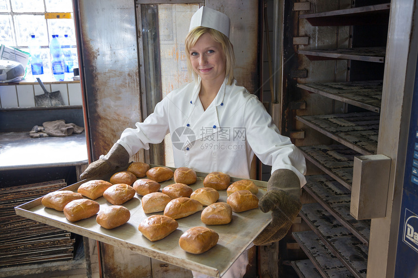 面包房或面包店的面包师将面包放入烤箱面团产品食物黄油面粉工作包子制造业糕点手工图片