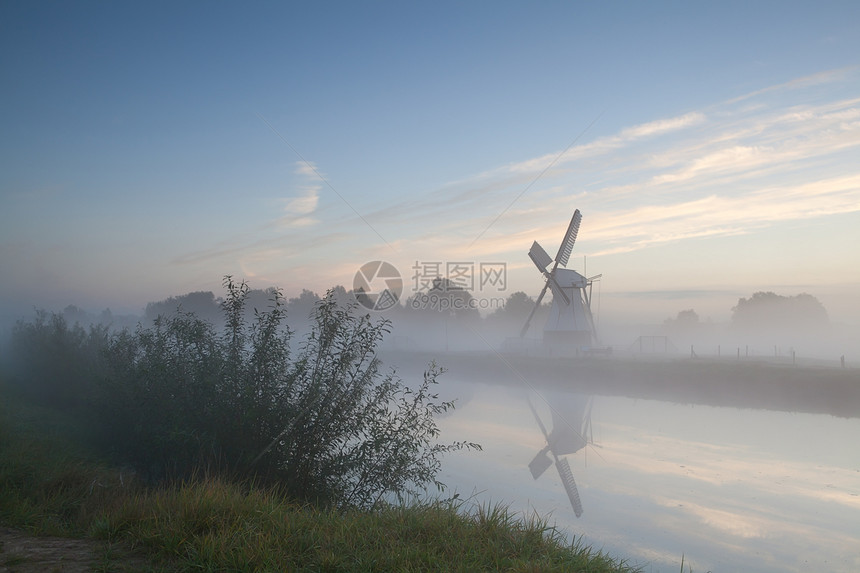清晨雾中河边的风车图片