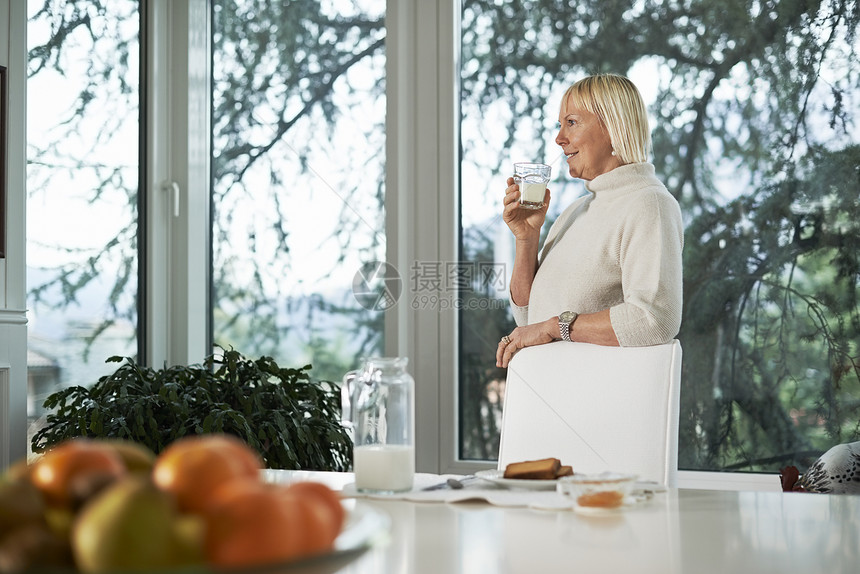高龄妇女用牛奶吃早餐的肖像奶制品玻璃水果祖母食物女性杯子快乐成人女士图片