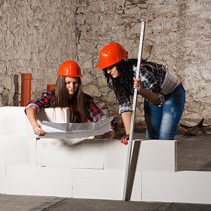 两个长头发的年轻女人 在街上筑了一道新墙维修建造工具房间力量建筑乐器安全帽子工作背景图片