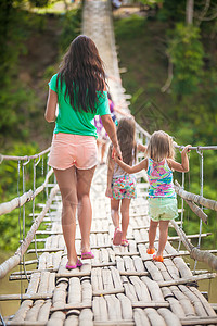 年轻母亲和她的小女儿在菲律宾罗博河悬索桥上的背影远足高清图片素材