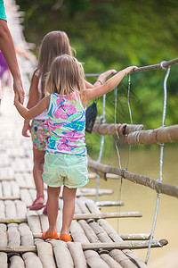 在菲律宾洛博克河上悬浮桥上行走的小女孩背视镜索桥高清图片素材