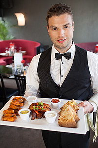 服务器提供服务英俊的侍应服务员 提供美味的手指食物盘背景