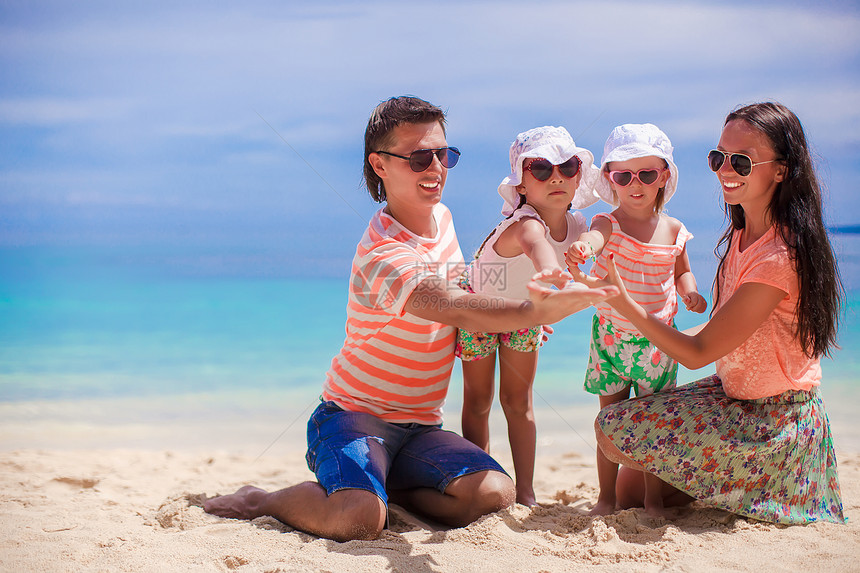 四口的年轻美丽家庭 享受沙滩上放松的快乐婴儿旅游母亲男性假期父母女儿女士热带情调图片