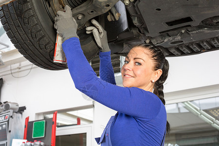 在液压坡道修理一辆汽车的机械机修理工职业工人车库工程师检查女性工具服务作坊车辆高清图片素材